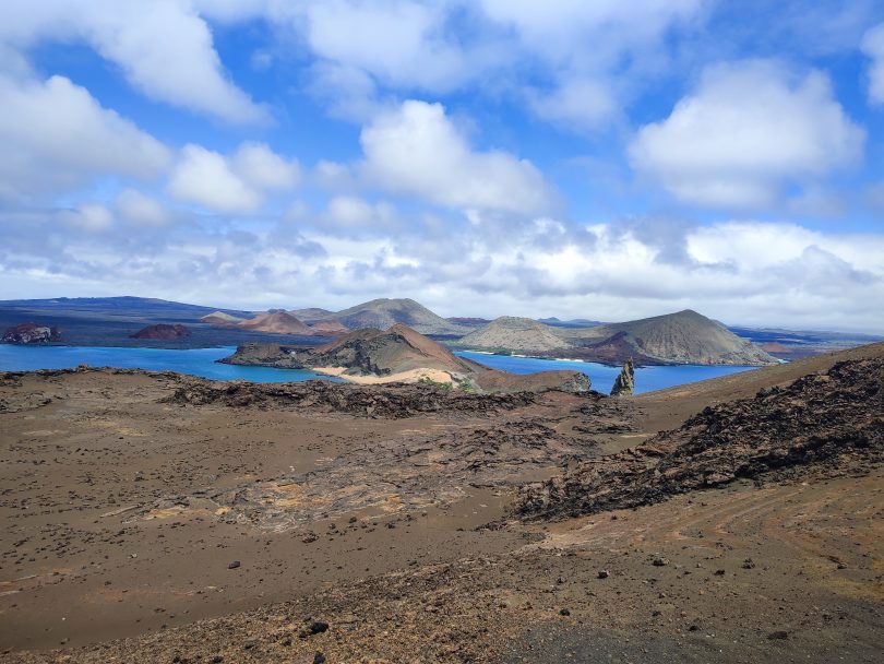 Scenic overlook of Bartolomé Island showing volcanic hills, bright blue bays and dramatic island terrain during a guided Galápagos tour with our agency