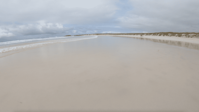 Wide sandy beach under cloudy March skies during the wet season, photographed on a Galapagos Islands cruise with Cruises to Galapagos Islands