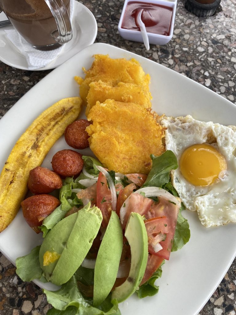 Plate of Ecuadorian llapingachos with fried egg, avocado, salad, sausage and plantain served during a Galápagos cruise with our agency